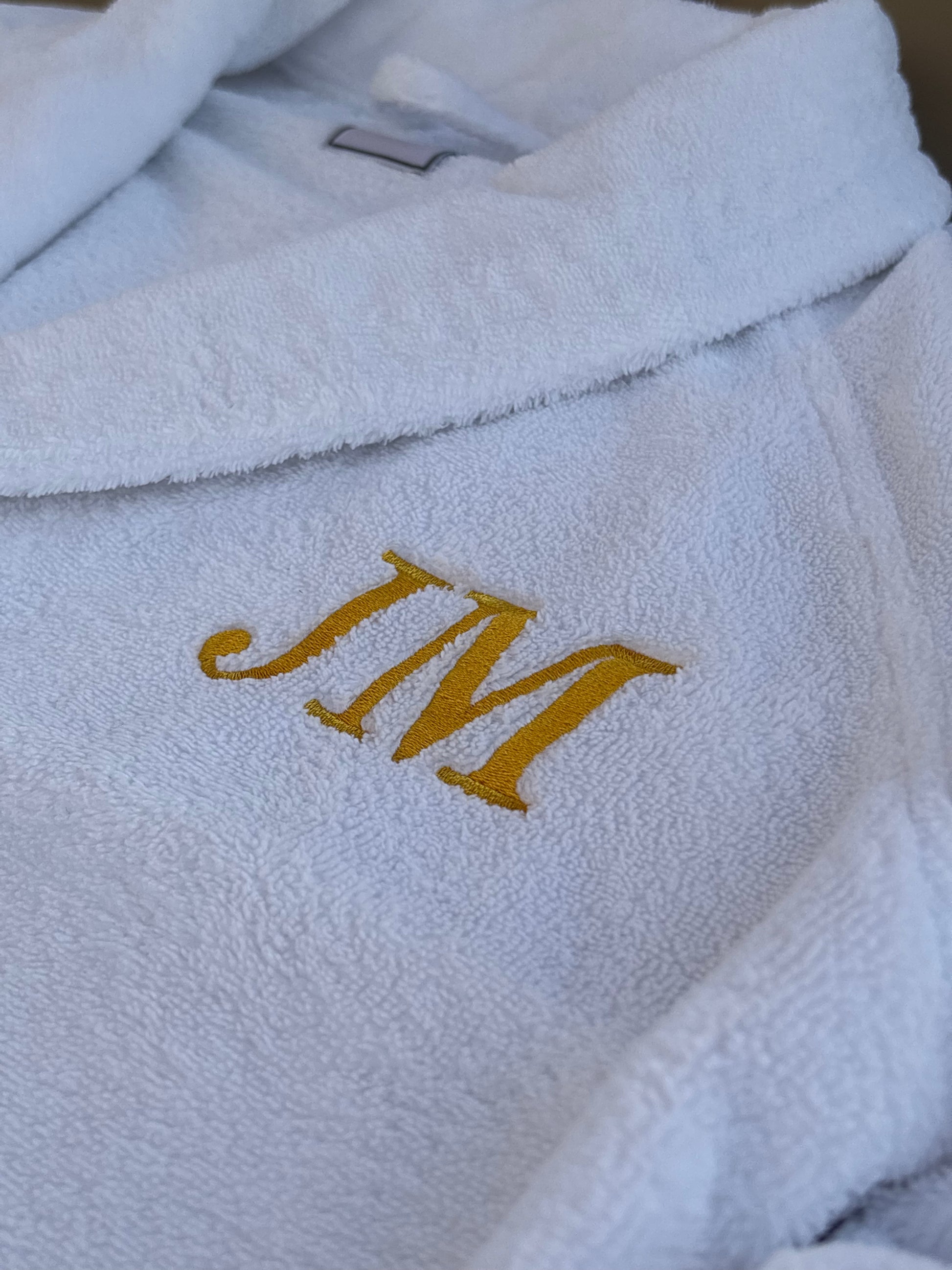 Initialen als Stick auf einem weißen Bademantel