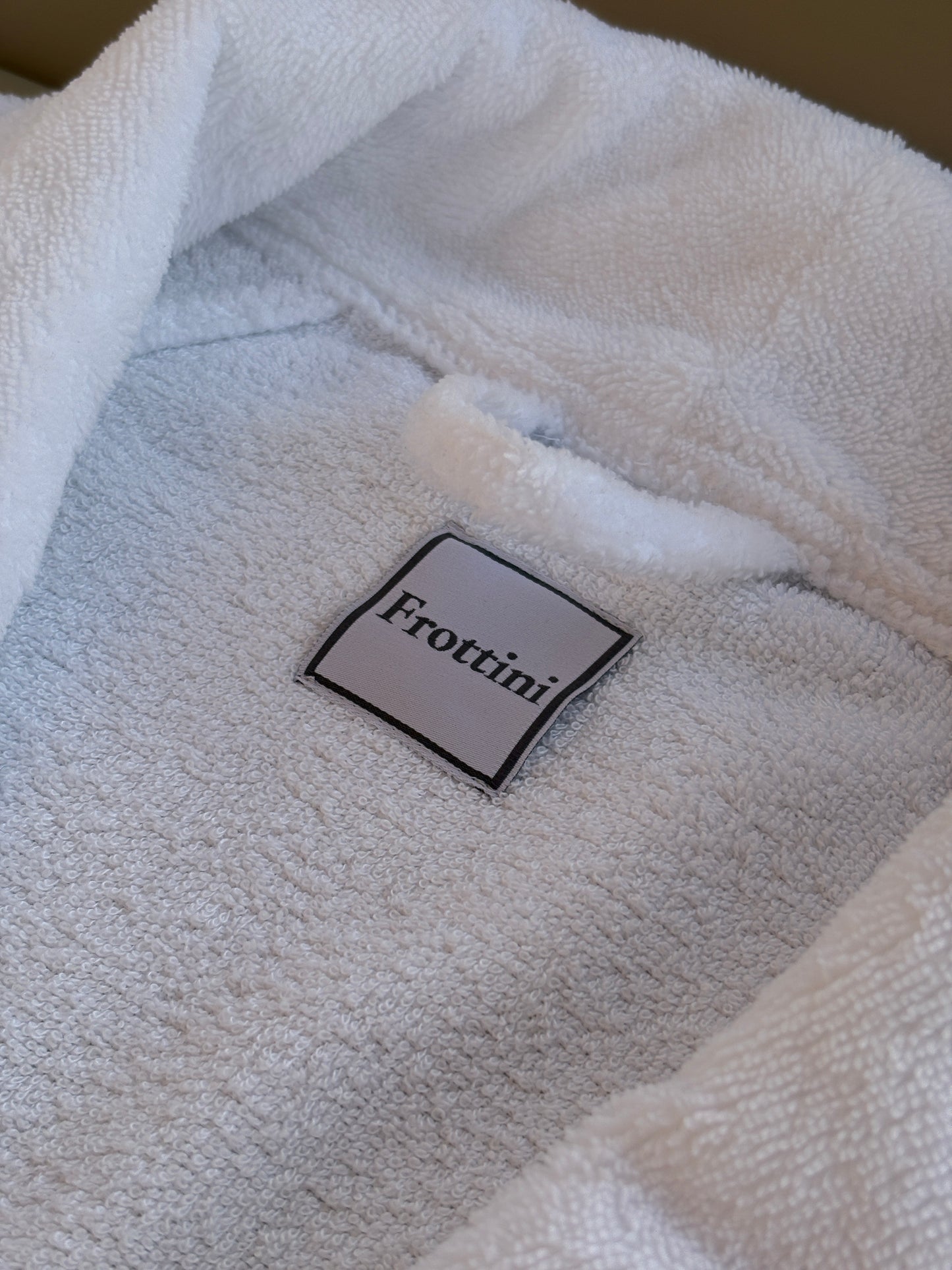 Detailaufnahme Frottini Markenlabel auf weißem Bademantel
