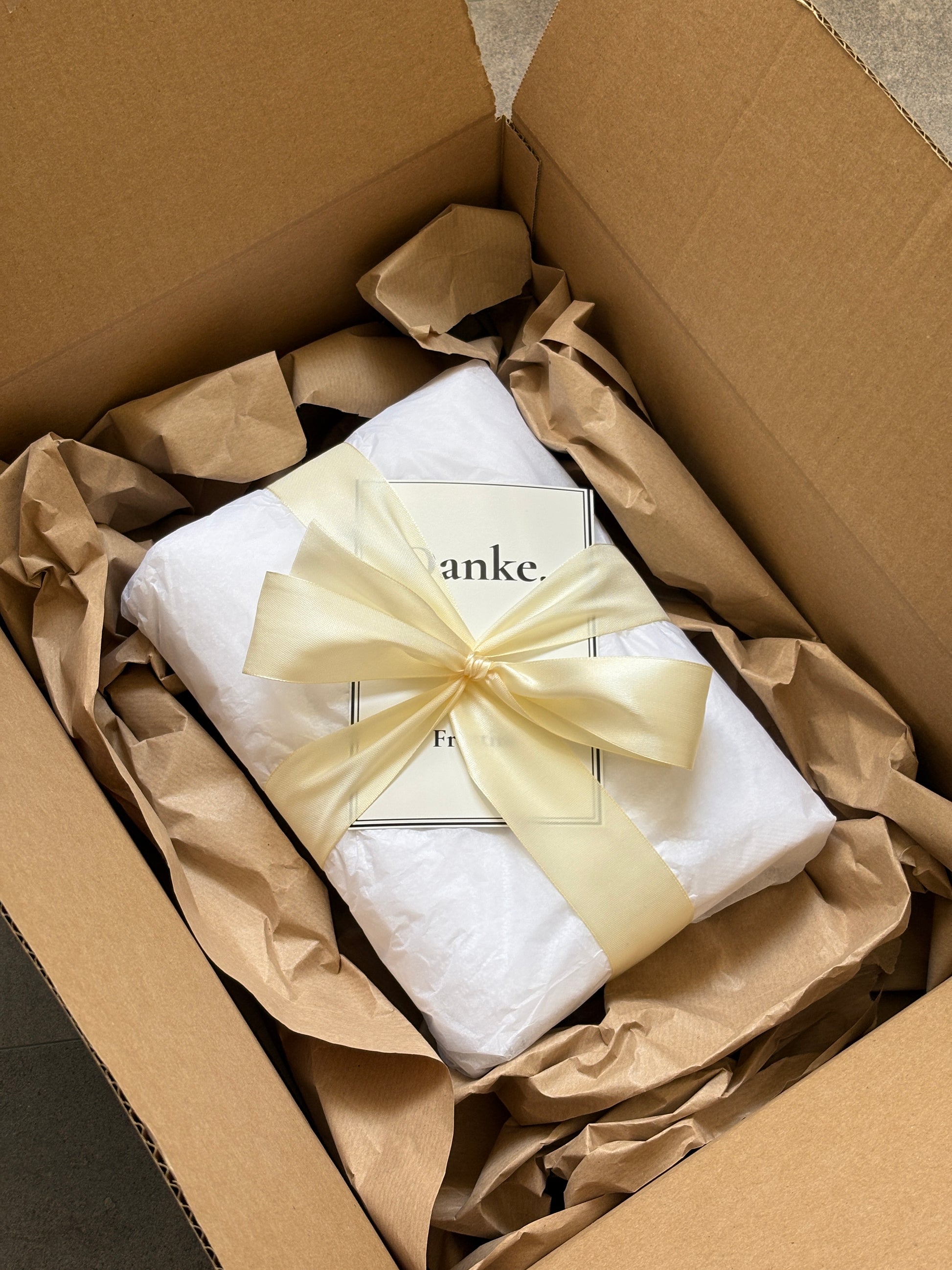 Geschenkverpacktes Handtuch mit Schleife und Dankeskarte im Versandkarton