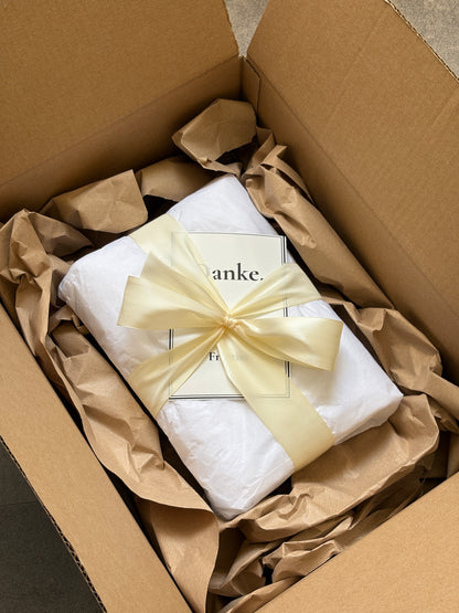 Geschenkverpacktes Handtuch mit Schleife und Dankeskarte im Versandkarton